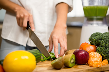 Women cutting vegetables while preparing food. 