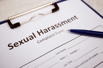 A close up of a sexual harassment complaint form on a desk with a pen