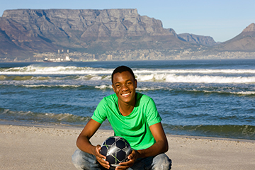Young male with soccer ball on beach